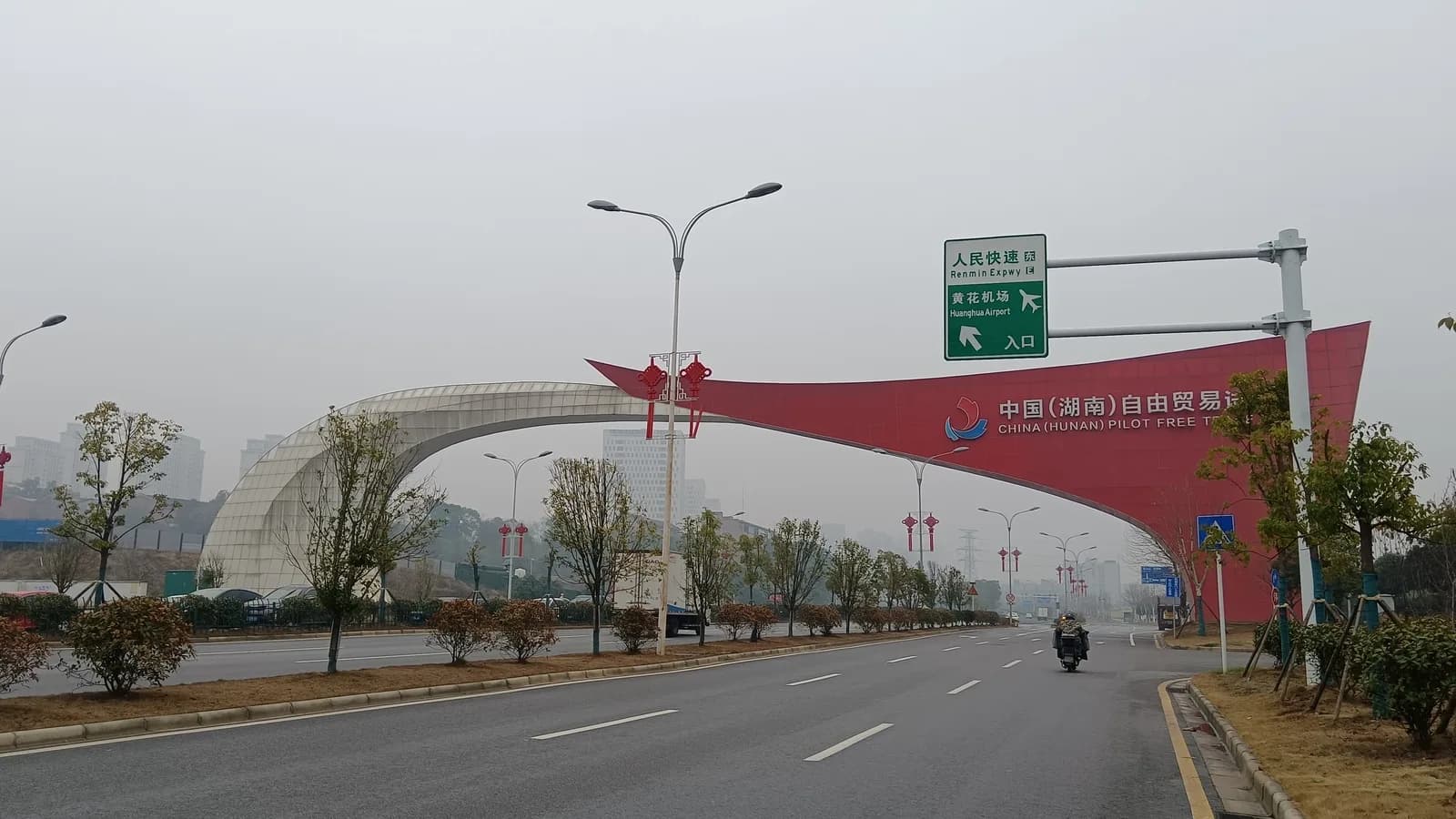 Pórtico vermelho de entrada da Zona de Livre Comércio de Hunan, na China, sobre uma avenida