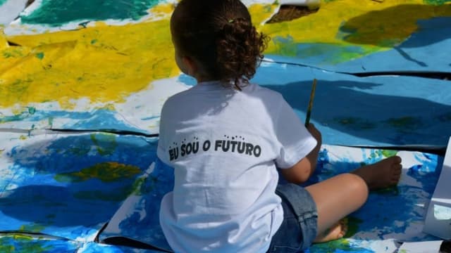 Criança brincando com tinta sobre painel colorido