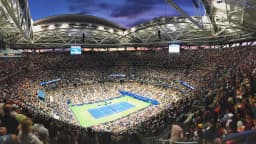 Arquibancadas lotadas da Arena Arthur Ashe durante partida noturna do US Open, com o público em volta da quadra