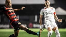 Jogador do Sport, de uniforme vermelho e preto, chuta a bola durante partida contra o Santos