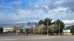 Fachada da sede da Meta em Menlo Park, na Califórnia, com o logo da empresa e o endereço 1 Hacker Way