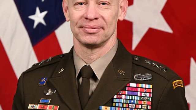 Retrato oficial do tenente-general Brett Sylvia, do Exército dos Estados Unidos, em frente a bandeiras americanas