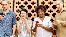 Grupo de quatro pessoas usando celulares lado a lado