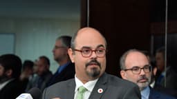 Mateus Simões fala a jornalistas em entrevista coletiva, de terno e com um pin da bandeira de Minas Gerais na lapela; imagem de arquivo de 2024