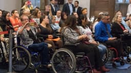 Pessoas com deficiência, várias em cadeira de rodas, reunidas em evento público
