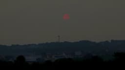 Sol avermelhado visto através da densa fumaça de queimadas sobre Manaus