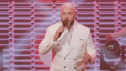 Belo se apresenta em show usando terno branco e cantando ao microfone, em imagem de arquivo