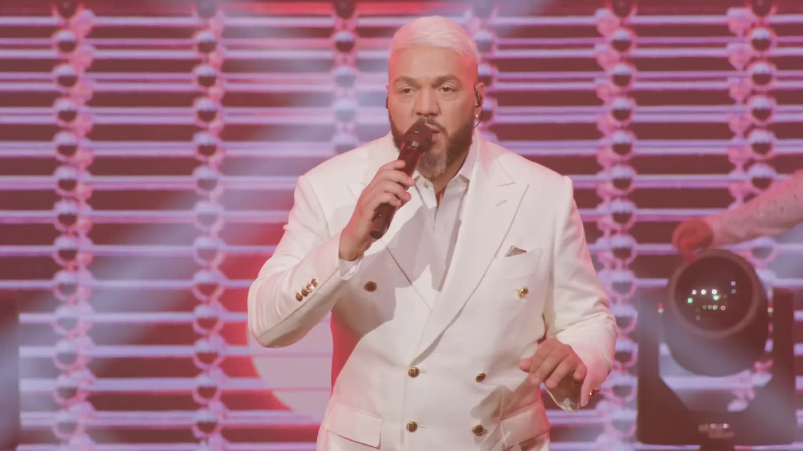 Belo se apresenta em show usando terno branco e cantando ao microfone, em imagem de arquivo