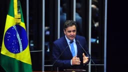 O senador e candidato Aécio Neves discursa em plenário, diante da bandeira do Brasil