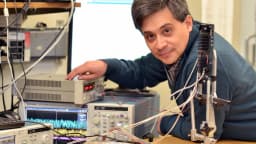 Pesquisador testa equipamento eletrônico ligado a computador em laboratório de tecnologia