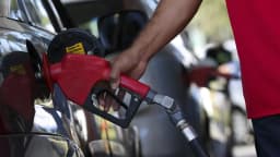 Mão de frentista abastece carro com combustível em posto de gasolina