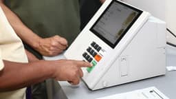 Mãos de eleitor e mesário em urna eletrônica durante votação