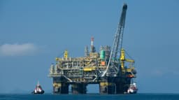 Plataforma de petróleo da Petrobras no mar, com rebocadores ao lado