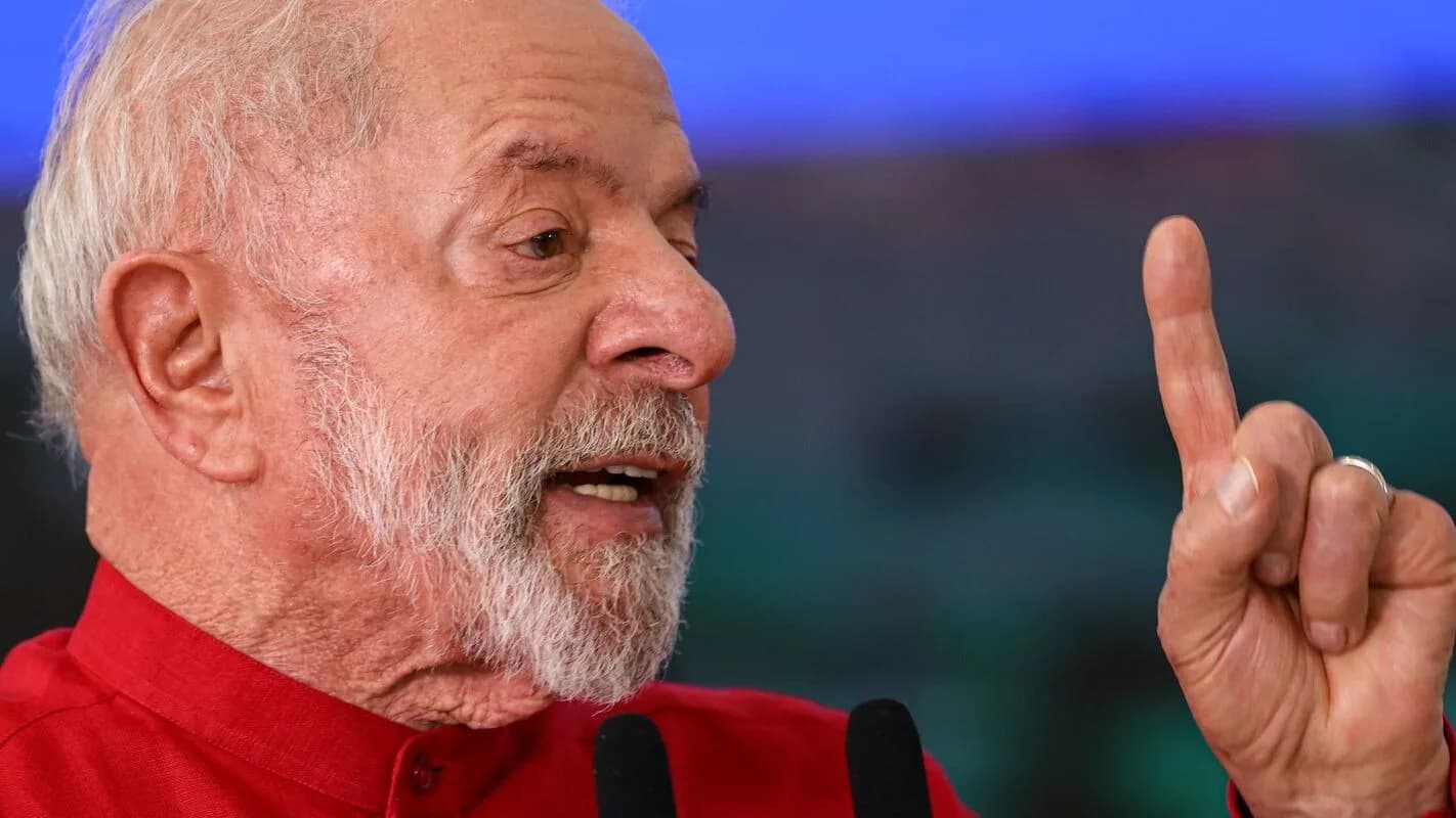 O presidente Lula fala em evento público, com o dedo indicador levantado, vestindo camisa vermelha