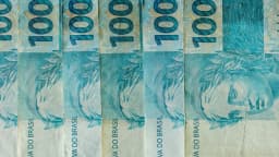 Cédulas de R$ 100 organizadas, representando o cenário fiscal e de investimentos no Brasil