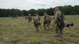 Soldados ucranianos caminham em fila por um campo durante treinamento militar