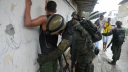 Agente de segurança revista suspeito durante operação policial no Rio de Janeiro