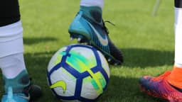 Chuteiras e bola de futebol sobre gramado, imagem ilustrativa do futebol brasileiro