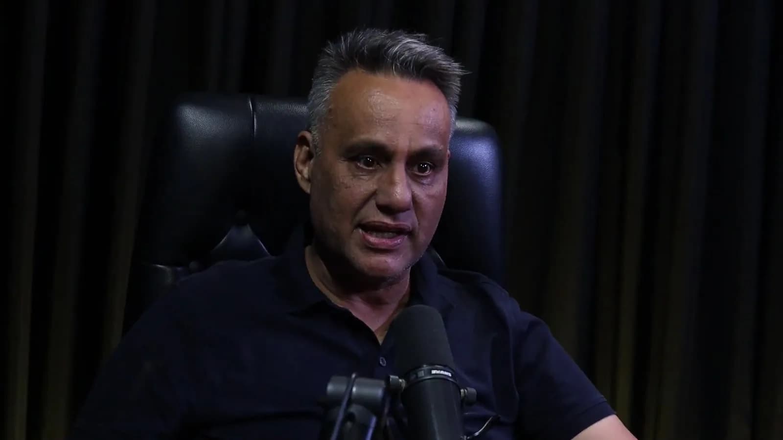 Rogério Furtado olha para cima enquanto fala durante o podcast Encampus, em cadeira de couro preta