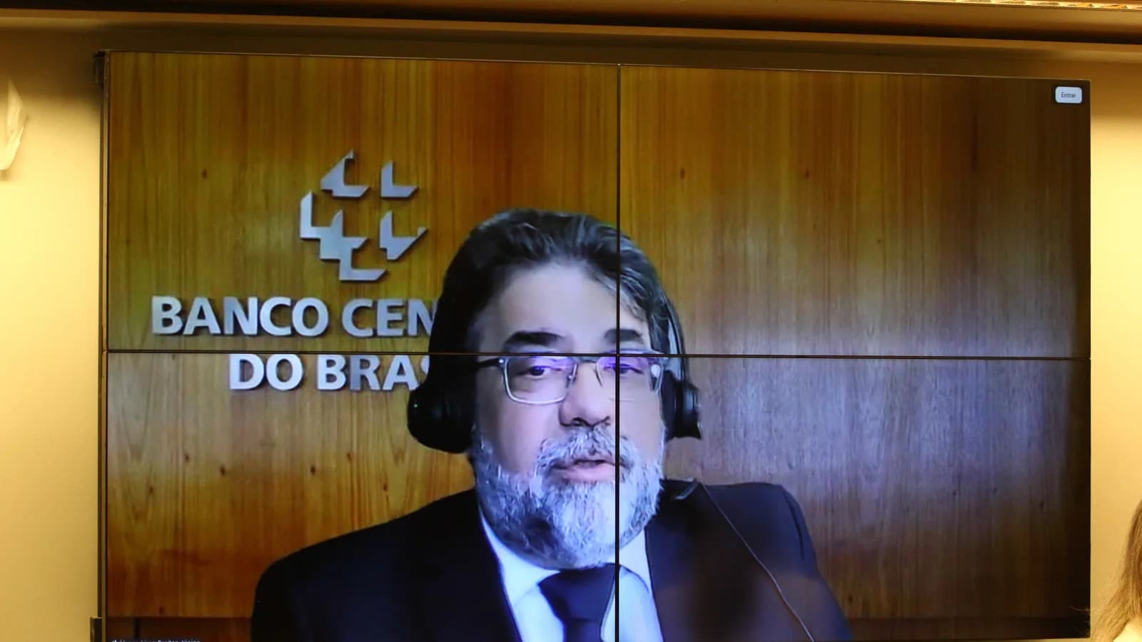 Representante do Banco Central participa de audiência pública por videoconferência, com o logo da instituição ao fundo