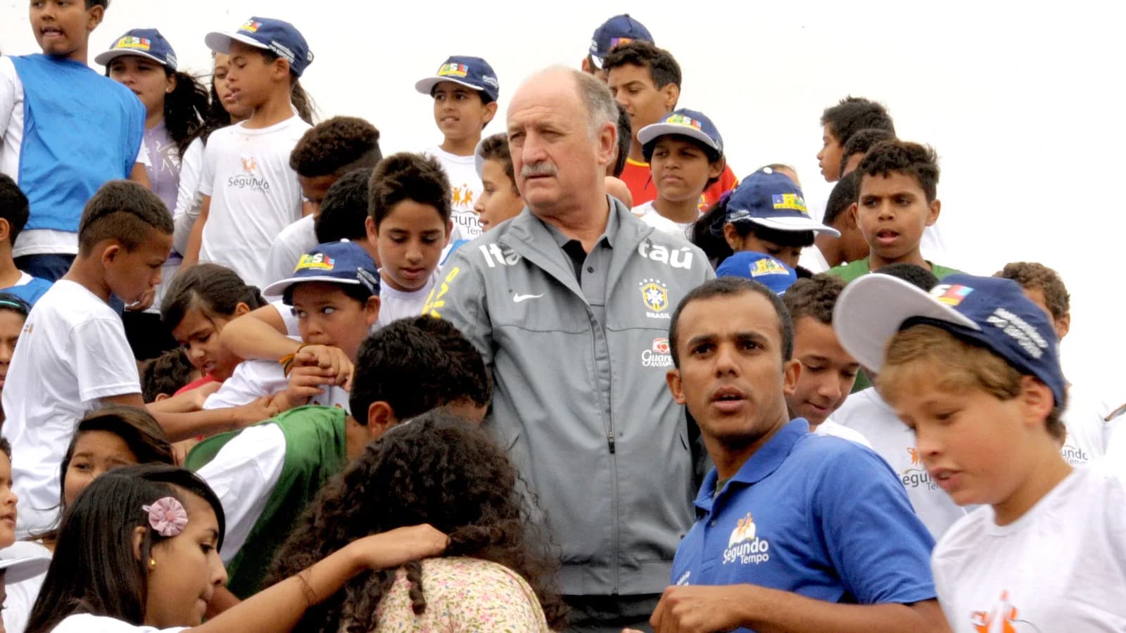 O técnico Felipão, de casaco da seleção brasileira, cercado por crianças em evento social, foto de arquivo