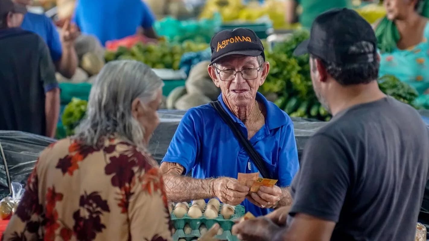 Vendedor atende cliente em feira livre, cena de comércio de pequeno porte no Brasil