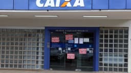 Fachada de agência da Caixa com cartazes de greve dos bancários colados no vidro