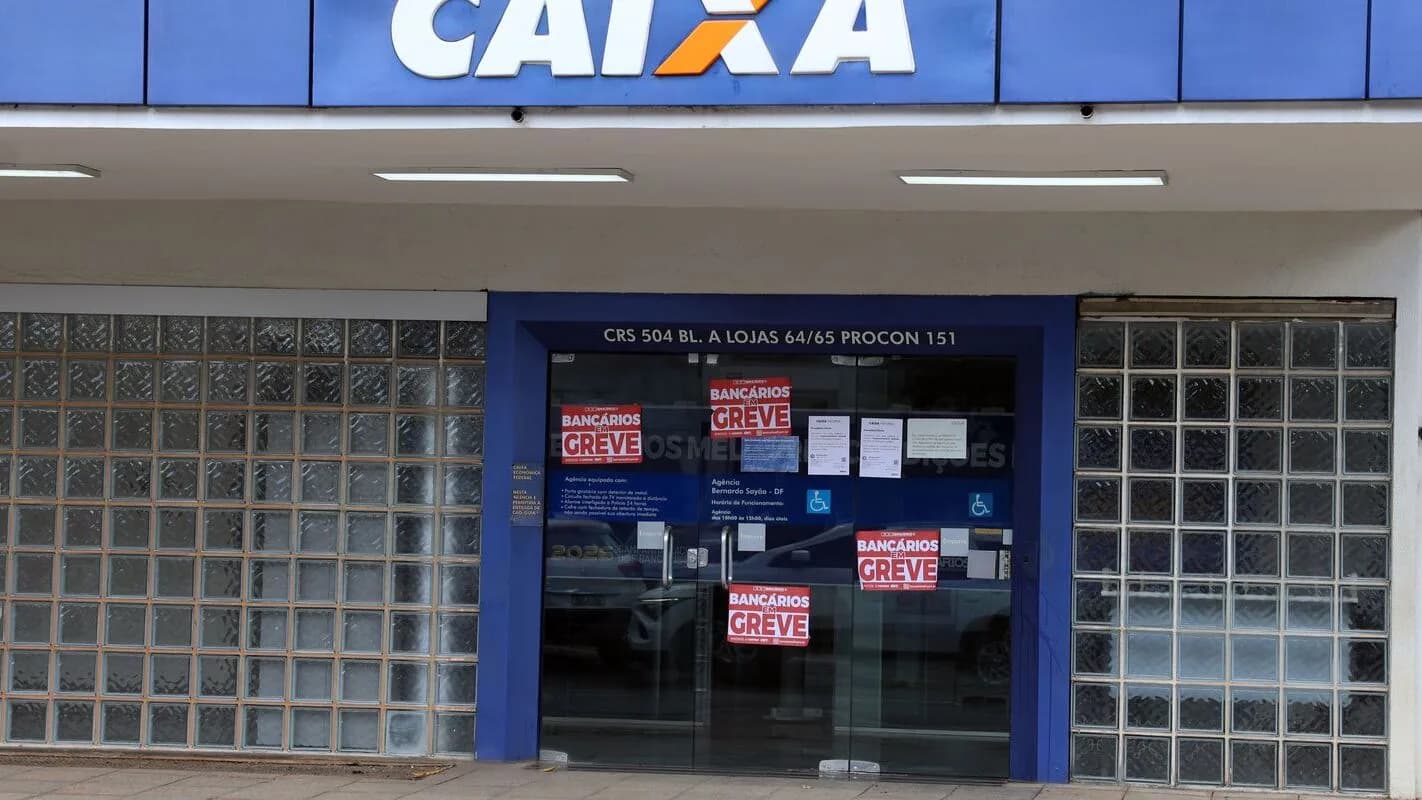 Fachada de agência da Caixa com cartazes de greve dos bancários colados no vidro