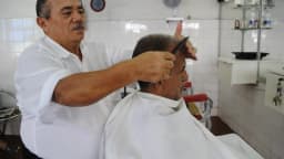 Barbeiro corta o cabelo de um cliente em barbearia (foto ilustrativa)