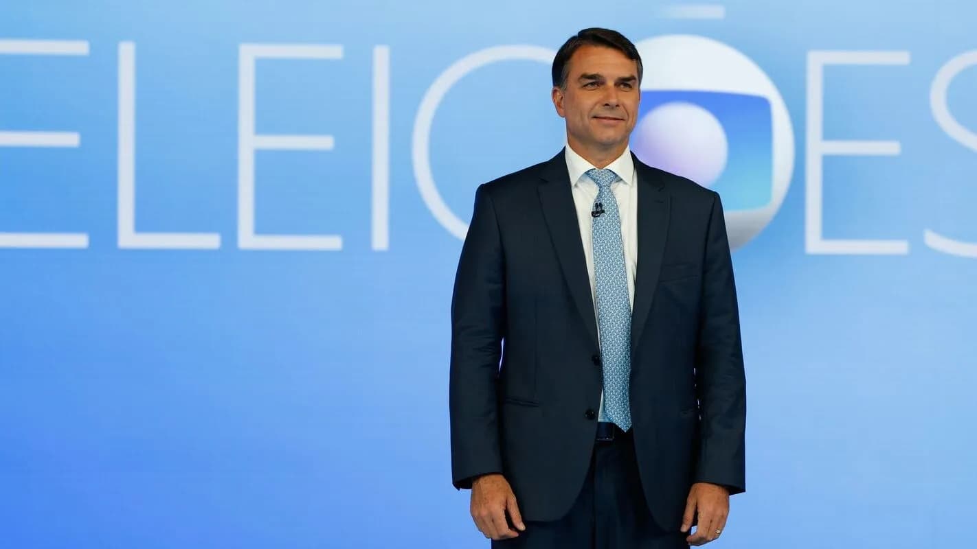 Flávio Bolsonaro em estúdio de TV com letreiro Eleições ao fundo