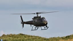 Helicóptero militar AS550 Fennec, mesmo modelo usado pela Dinamarca, voando sobre área gramada