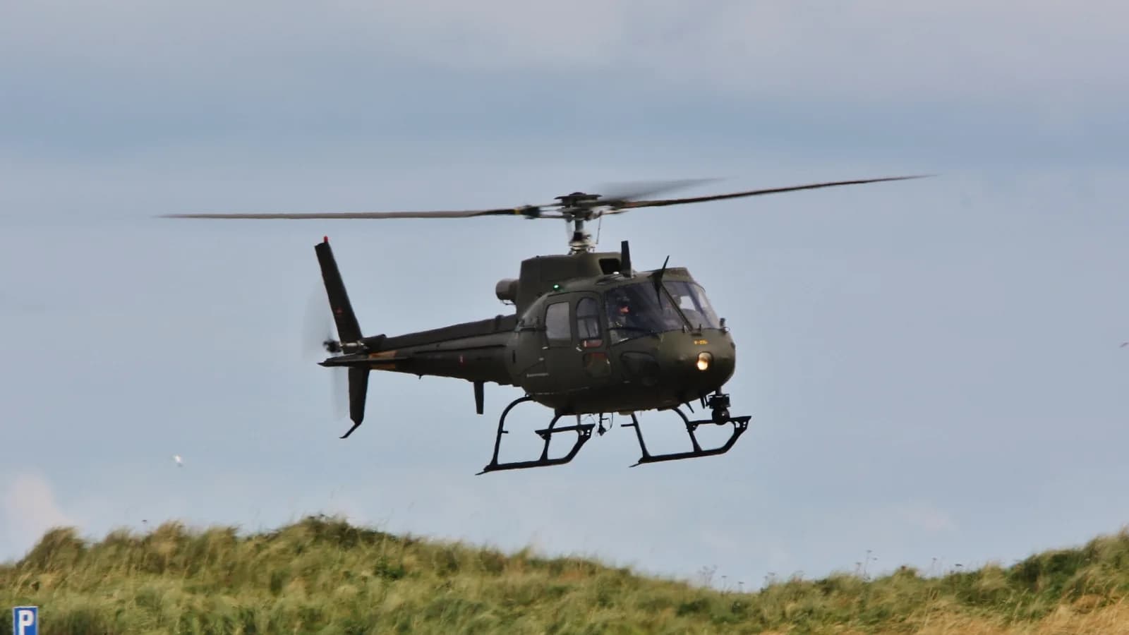 Helicóptero militar AS550 Fennec, mesmo modelo usado pela Dinamarca, voando sobre área gramada