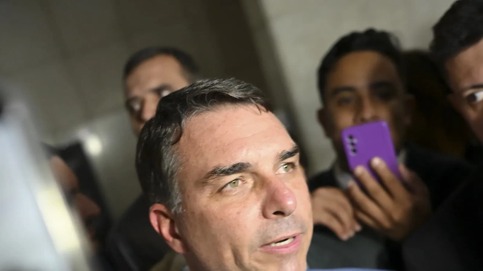 Senador Flávio Bolsonaro fala à imprensa cercado de microfones e repórteres no Senado
