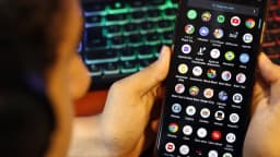 Pessoa segura um celular com aplicativos de assistentes de inteligência artificial na tela