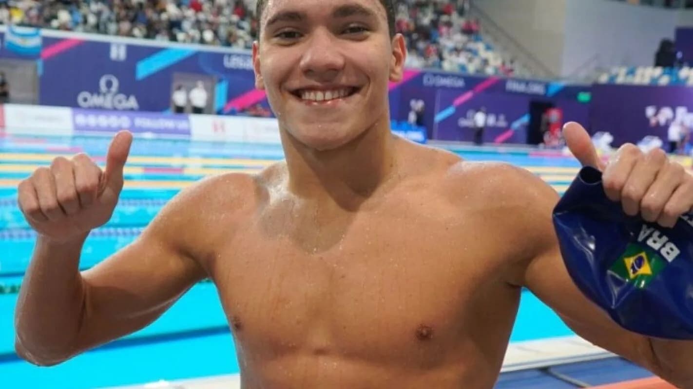 Stephan Steverink comemora com os polegares para cima ao lado da piscina, segurando a touca do Brasil