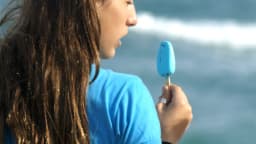 Jovem come picolé gelado à beira-mar
