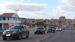 Carreata de campanha eleitoral com carros enfileirados e bandeiras em via pública