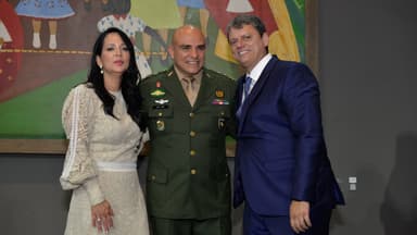 Tarcísio de Freitas sorri ao lado de um coronel e de uma convidada em cerimônia oficial (foto de arquivo)