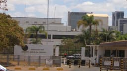 Fachada da embaixada dos Estados Unidos em Brasília, com bandeira americana e placa de identificação do prédio