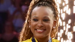 Rebeca Andrade sorri com medalha e uniforme amarelo da seleção brasileira de ginástica