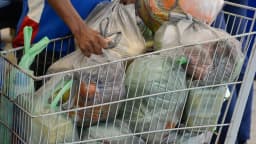 Pessoa coloca sacolas de compras de alimentos em carrinho de supermercado