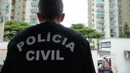 Policial da Polícia Civil visto de costas, com a farda estampada 'Polícia Civil', em foto de arquivo de ação da corporação