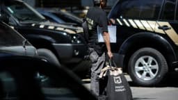Agente da Polícia Federal carrega material durante operação
