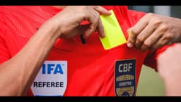 Árbitro de futebol brasileiro guarda cartão amarelo no bolso da camisa, com emblema da CBF (foto de arquivo, ilustrativa)