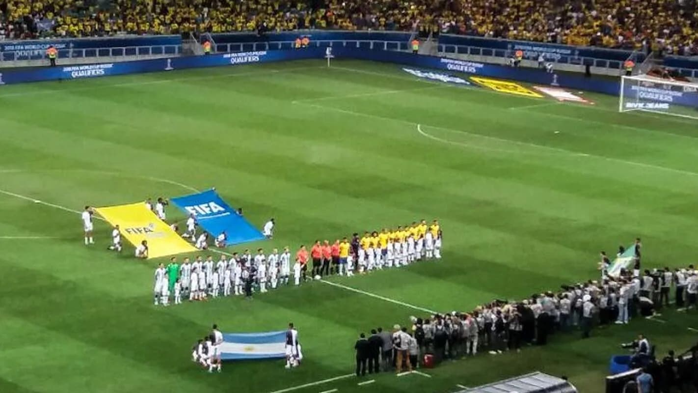 Bandeira gigante é carregada por torcedores em campo antes de partida de futebol