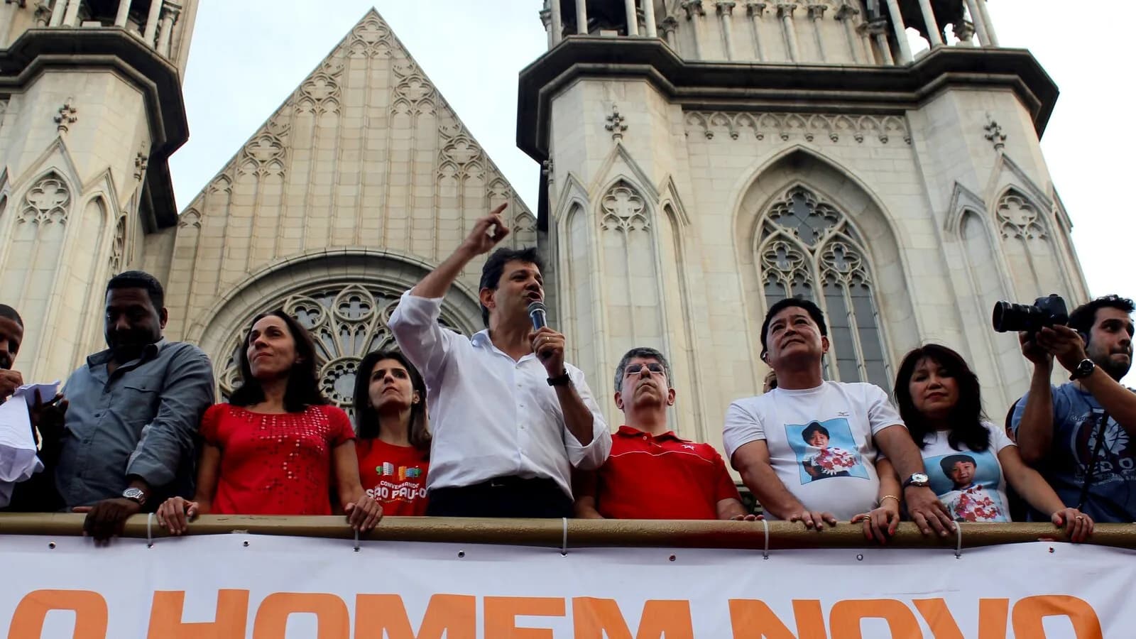 Fernando Haddad discursa ao microfone diante da Catedral da Sé, em São Paulo, cercado de apoiadores