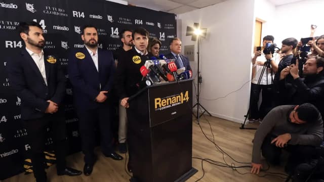 Renan Santos discursa em coletiva de imprensa com material de campanha ao fundo