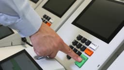 Mão de eleitor digitando número em urna eletrônica brasileira