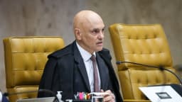 Alexandre de Moraes gesticula durante sessão do STF, sentado à mesa com cadeira de couro