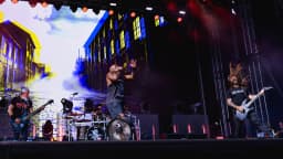 Sepultura se apresenta ao vivo no palco, com o baterista atrás do bumbo escrito Sepultura 40